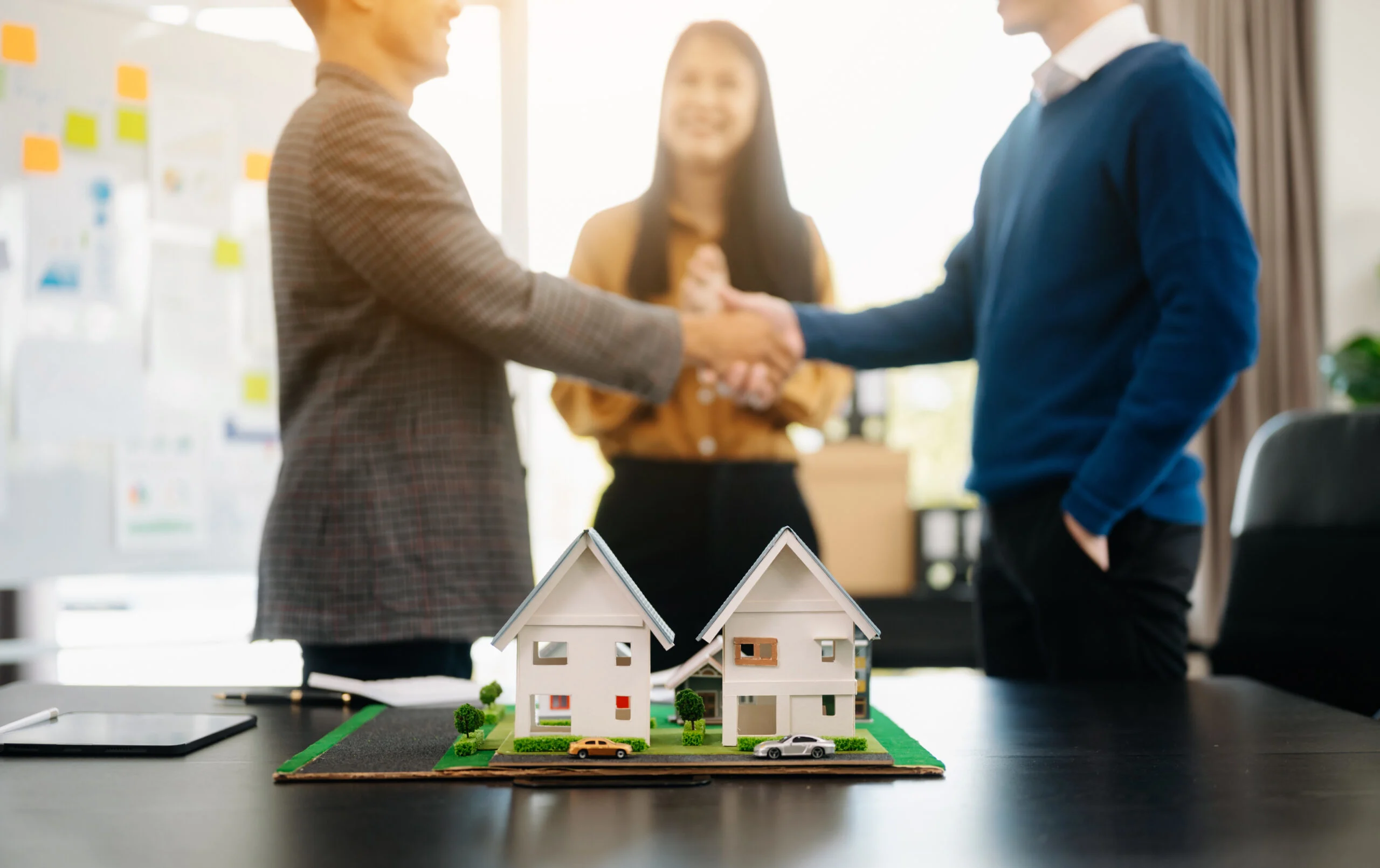 Property professionals shaking hands beside model homes